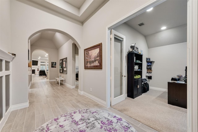 corridor with arched walkways, vaulted ceiling, baseboards, visible vents, and recessed lighting