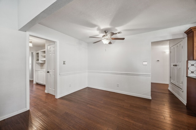 empty room with baseboards, visible vents, a ceiling fan, and dark wood-style floors