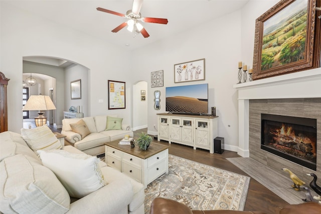 3204 Discovery Dr, Little Elm, TX 75068 - living area with arched walkways, ceiling fan, a tiled fireplace, dark wood-style floors, and baseboards