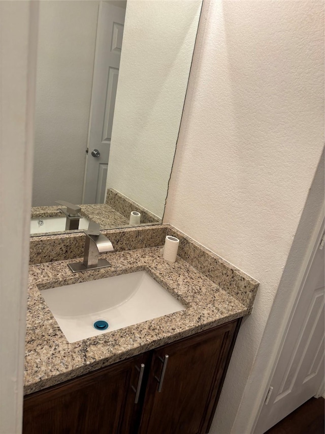 bathroom with a textured wall and vanity