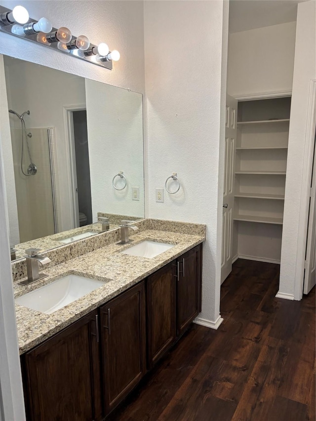 bathroom featuring baseboards, wood finished floors, a sink, and a shower
