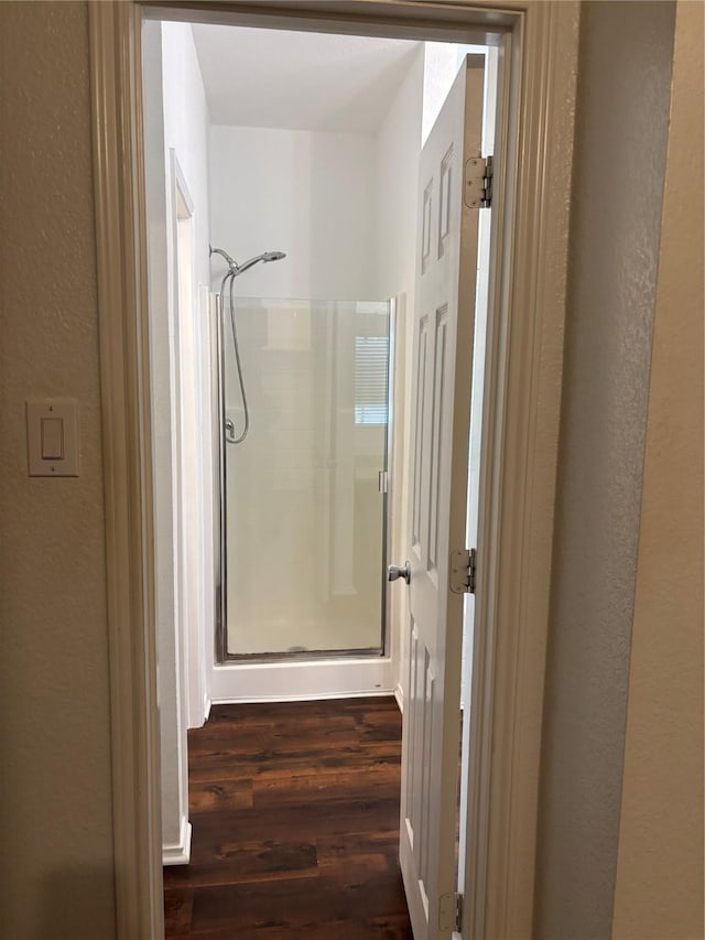 hall featuring a textured wall and dark wood-style floors