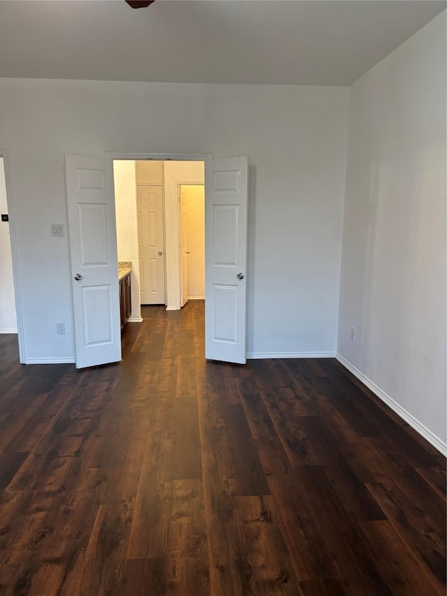 unfurnished room with baseboards and dark wood-style floors