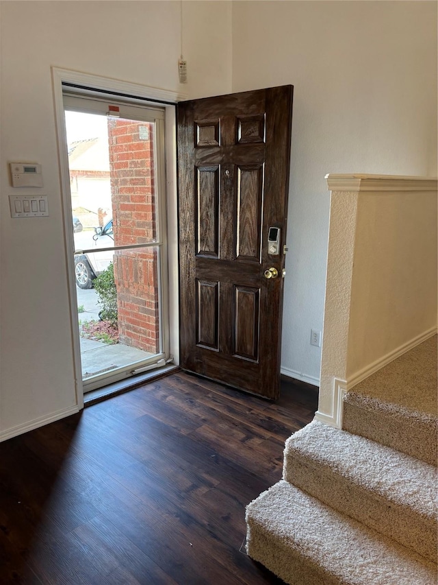 foyer featuring dark wood-type flooring, stairs, and baseboards