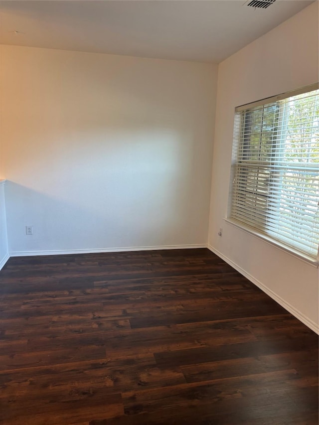 unfurnished room with baseboards, dark wood-type flooring, and visible vents