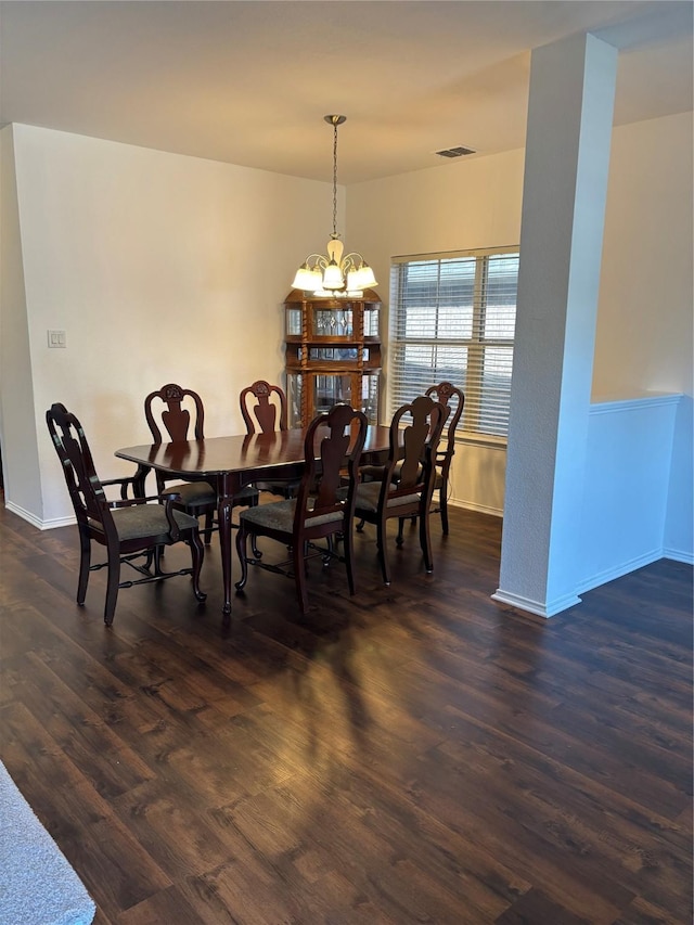 dining space with dark wood finished floors, an inviting chandelier, visible vents, and baseboards