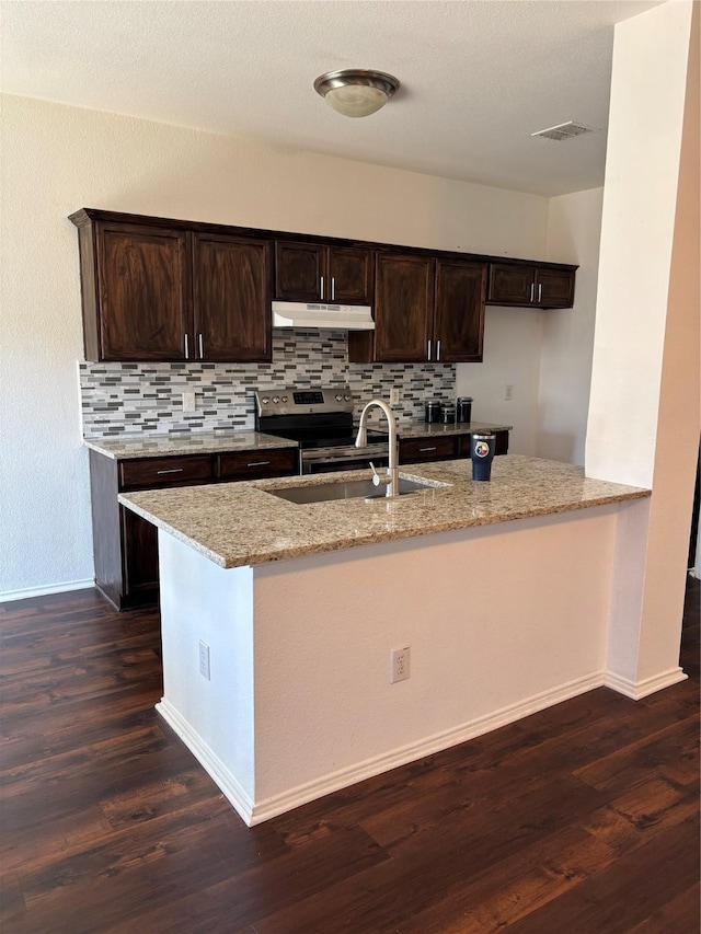 kitchen with stainless steel range with electric cooktop, under cabinet range hood, visible vents, a sink, and light stone countertops