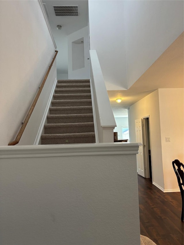 stairway with baseboards, wood finished floors, and visible vents