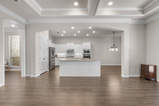 kitchen with ornamental molding, arched walkways, appliances with stainless steel finishes, under cabinet range hood, and dark wood-style floors