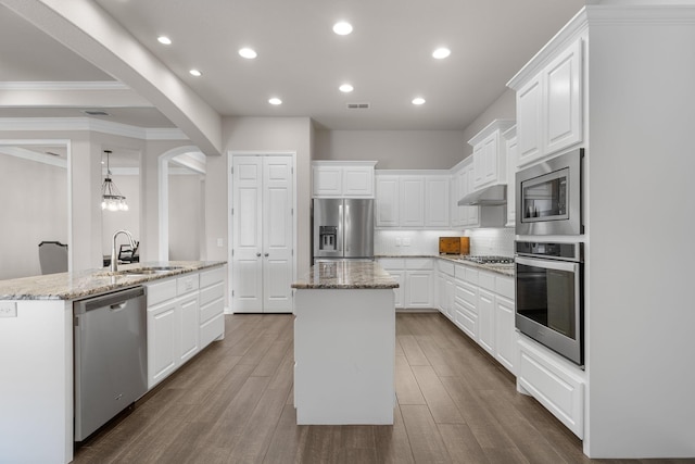 kitchen featuring crown molding, an island with sink, stainless steel appliances, and a sink
