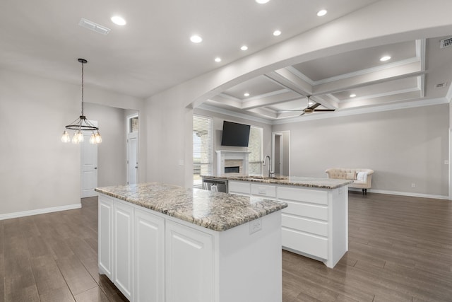 kitchen featuring wood finished floors, ceiling fan with notable chandelier, open floor plan, an island with sink, and arched walkways