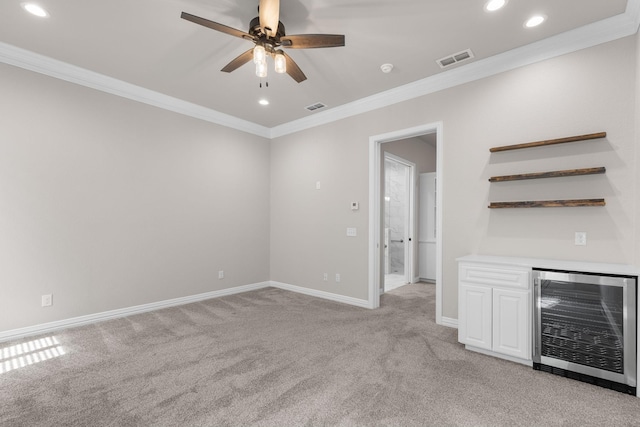unfurnished living room with light carpet, visible vents, beverage cooler, and crown molding