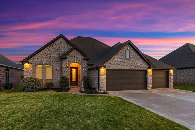 french country style house featuring an attached garage, brick siding, a front yard, and concrete driveway