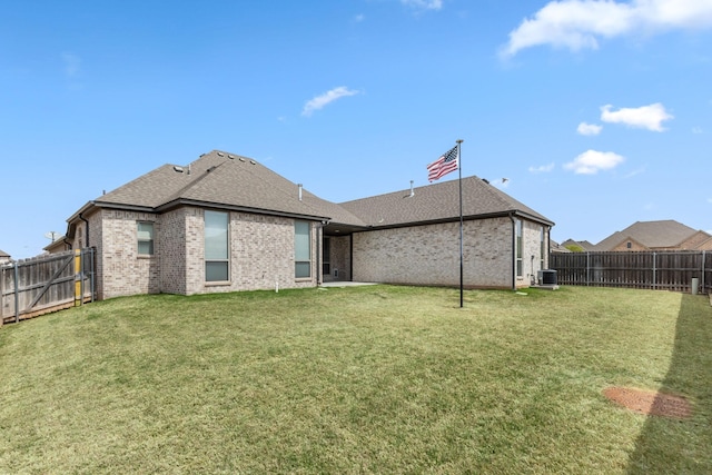 back of house with brick siding, cooling unit, a lawn, and a fenced backyard
