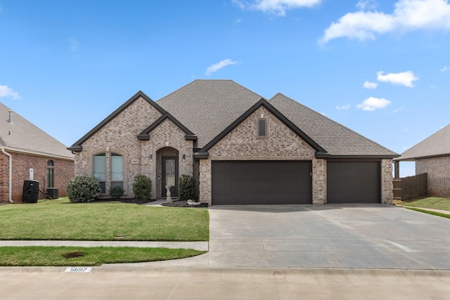 french country home with a front lawn, central air condition unit, driveway, brick siding, and a garage