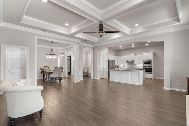 living area featuring arched walkways, baseboards, dark wood-style floors, and ornamental molding