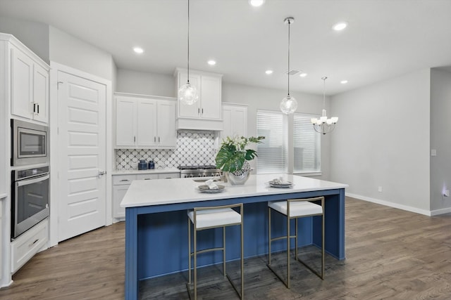 kitchen with a chandelier, stainless steel appliances, tasteful backsplash, a kitchen island, and white cabinets
