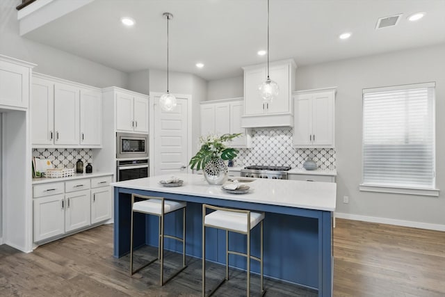 kitchen featuring visible vents, white cabinets, stainless steel appliances, and tasteful backsplash