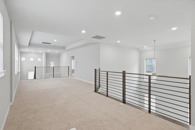 carpeted empty room featuring recessed lighting, a tray ceiling, visible vents, and baseboards