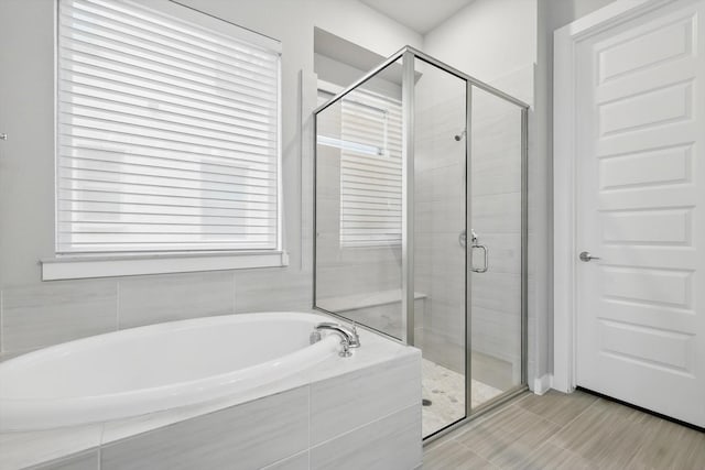 full bathroom with a shower stall and a bath