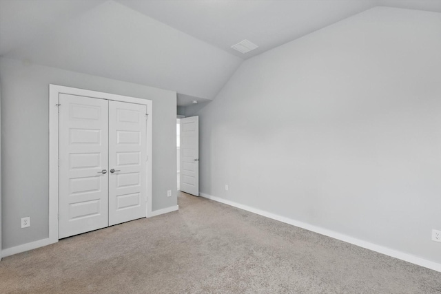 unfurnished bedroom featuring a closet, carpet flooring, lofted ceiling, and baseboards