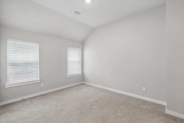 spare room with visible vents, vaulted ceiling, carpet, and baseboards