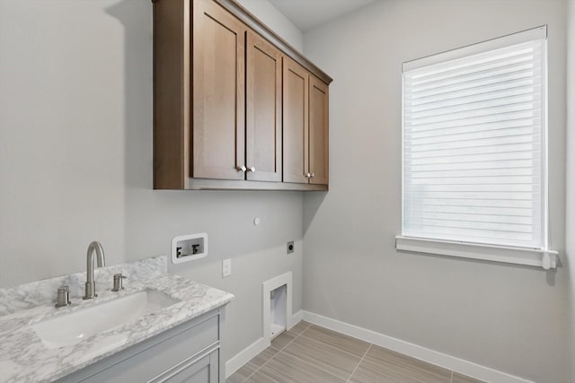 laundry area featuring hookup for an electric dryer, washer hookup, a sink, baseboards, and cabinet space