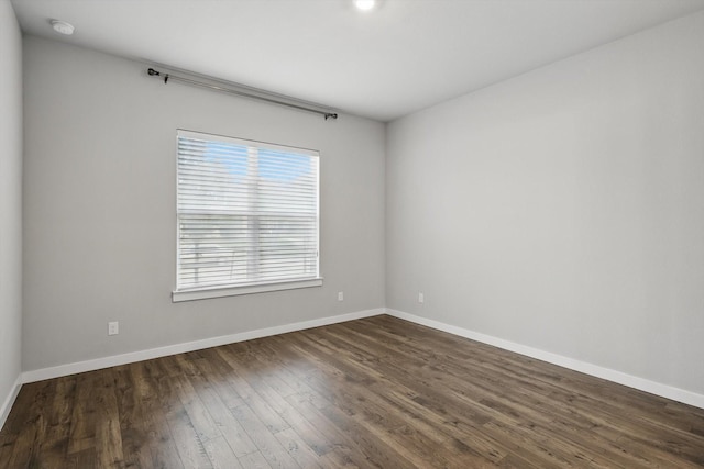 empty room featuring dark wood-style flooring and baseboards