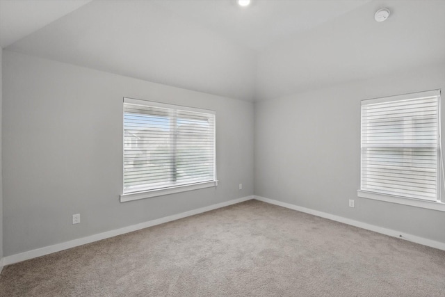 unfurnished room featuring carpet flooring, baseboards, and lofted ceiling