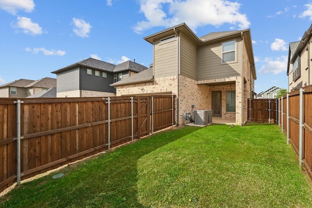 rear view of property with central air condition unit, a yard, a fenced backyard, a gate, and brick siding