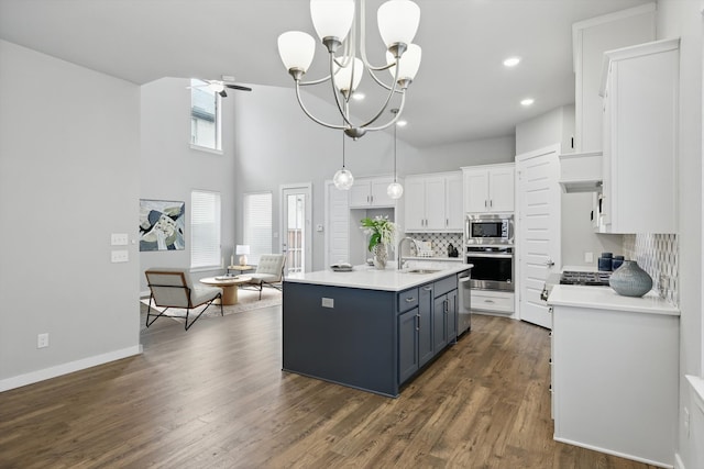 kitchen with tasteful backsplash, white cabinets, a sink, appliances with stainless steel finishes, and light countertops