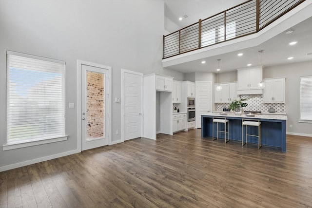 kitchen featuring stainless steel appliances, light countertops, white cabinets, backsplash, and a high ceiling
