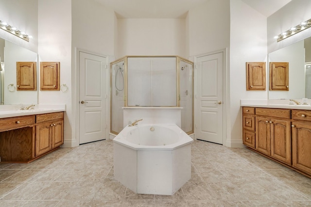 bathroom with a shower stall, a high ceiling, a bath, and two vanities