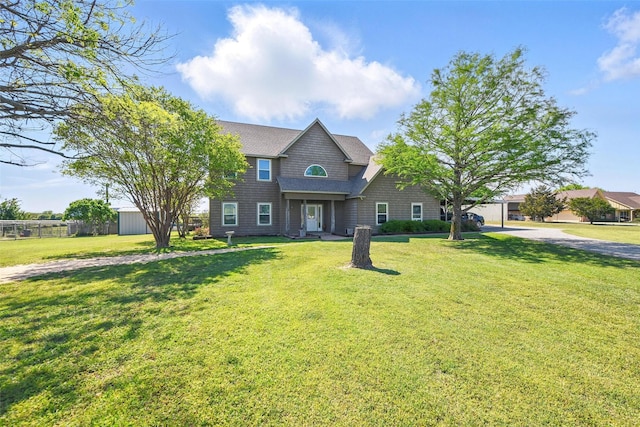 traditional-style home with fence, roof with shingles, and a front yard