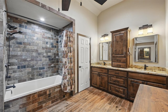 bathroom featuring tiled shower / bath, wood finished floors, double vanity, and a sink