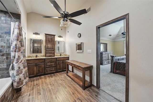 ensuite bathroom featuring a ceiling fan, wood finished floors, a sink, and double vanity