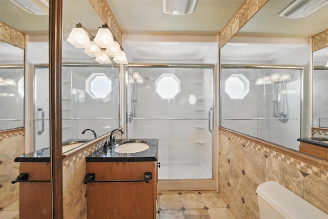 full bathroom featuring toilet, tile walls, tile patterned flooring, a shower stall, and vanity