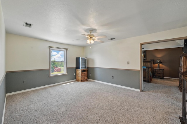 carpeted empty room featuring visible vents, baseboards, and ceiling fan