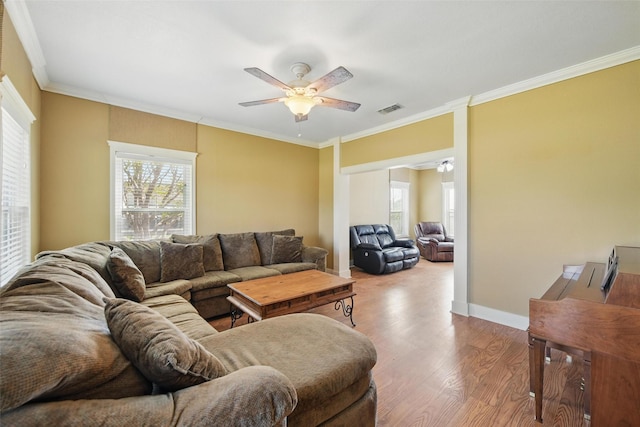 living area featuring wood finished floors, a ceiling fan, visible vents, and a wealth of natural light
