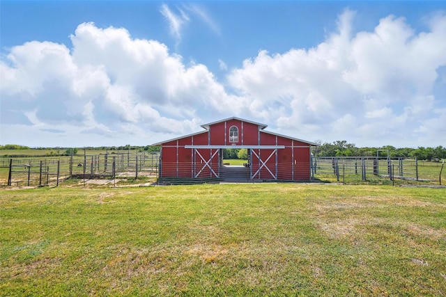 view of barn featuring fence, a yard, and a rural view