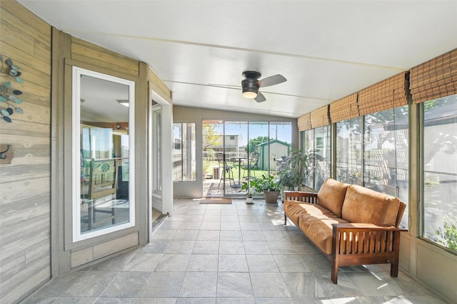 sunroom with ceiling fan, vaulted ceiling, outdoor lounge area, and stone finish flooring