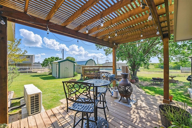 wooden terrace with outdoor dining space, fence, an outbuilding, a yard, and a storage unit