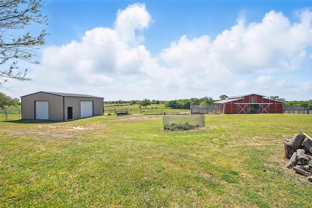 view of yard with a barn, fence, a rural view, an outdoor structure, and a detached garage