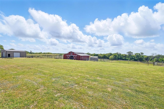 view of yard featuring a garage, an outbuilding, a rural view, and fence