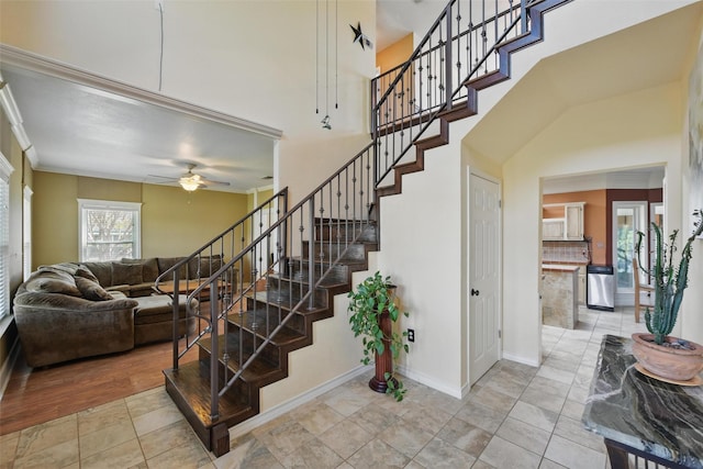 stairs featuring ceiling fan, baseboards, and ornamental molding