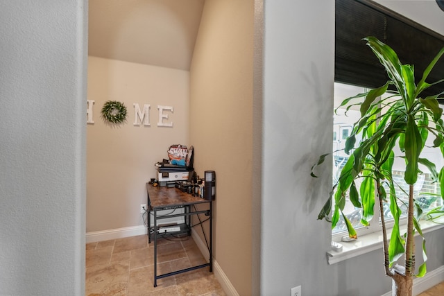 hall featuring lofted ceiling and baseboards