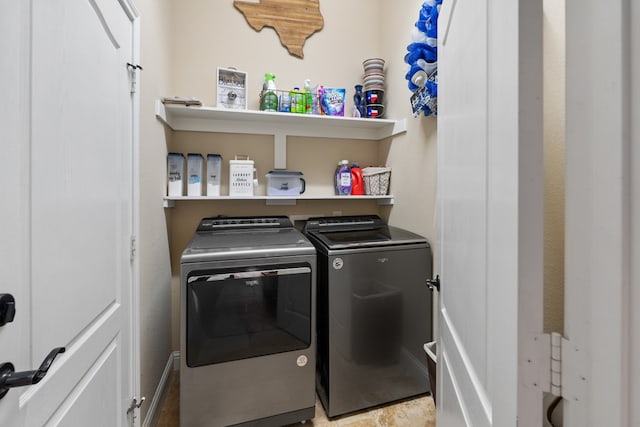 clothes washing area featuring baseboards, washer and dryer, and laundry area