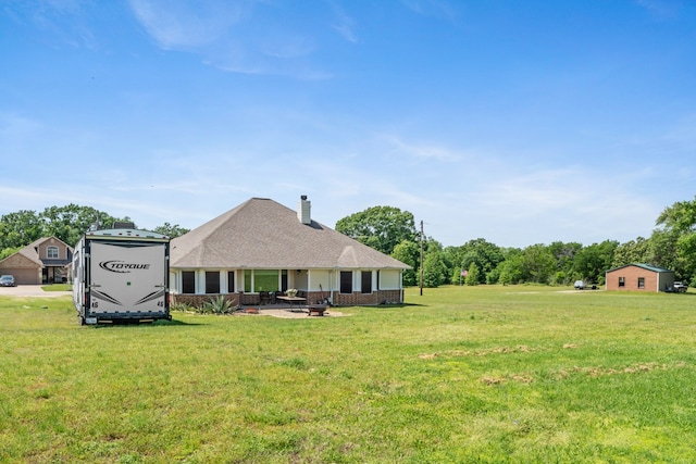 rear view of property featuring a chimney, a yard, a patio, an outdoor fire pit, and brick siding