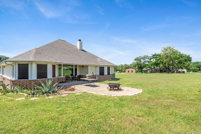 rear view of house with a patio area, a chimney, a lawn, a fire pit, and brick siding