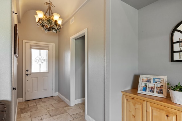 foyer featuring stone tile floors, baseboards, and a chandelier